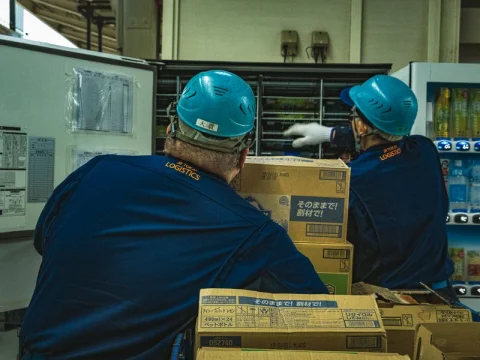 Warehouse workers in hard hats handling boxes